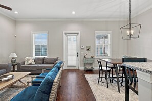 A modern living room with a sofa, coffee table, and dining area with chairs and a table. - 400 Ocean Blvd-  3-bedroom condo steps from pier and village (St. Simons Island)