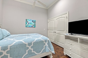 A bedroom with a bed, a television on a stand, a wardrobe, and a ceiling fan. - 400 Ocean Blvd-  3-bedroom condo steps from pier and village (St. Simons Island)