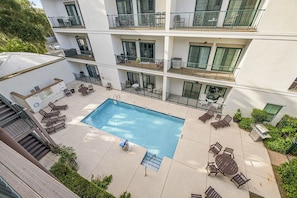 Een meerhoog gebouw met een zwembad, terras en balkons.