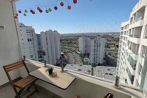 Ein Balkon mit Blick auf einen Stadtblick, einschließlich Wolkenkratzern und einem Parkplatz.