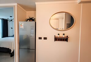 Ein Hotelzimmer mit Kühlschrank, Spiegel und einer kleinen Ablage mit Pflanzen.