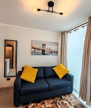 Ein modernes Wohnzimmer mit einem dunkelblauen Sofa, zwei gelben Kissen, einem städtischen Stadtbild als Gemälde, einem Spiegel und einem gemusterten Teppich.