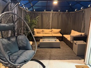A cozy outdoor seating area with a swing chair, a sofa, and a coffee table.