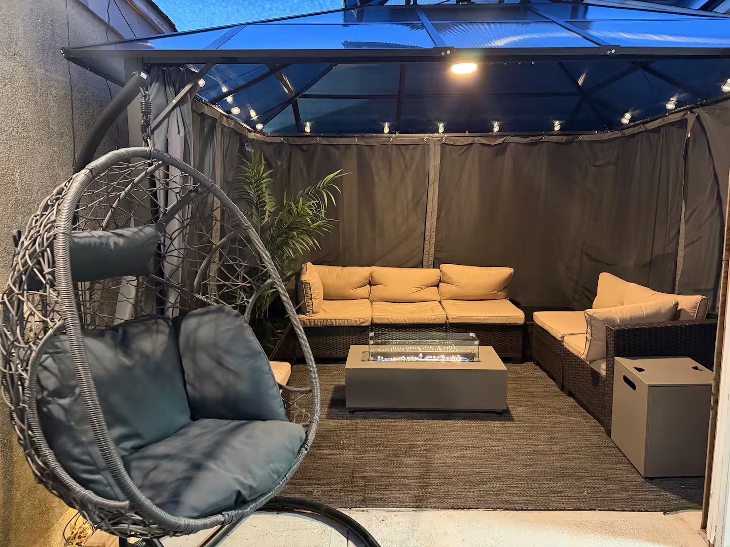 A patio area with a hanging chair, a sofa, and a coffee table.