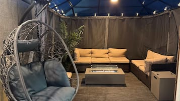 A patio area with a hanging chair, a sofa, and a coffee table.
