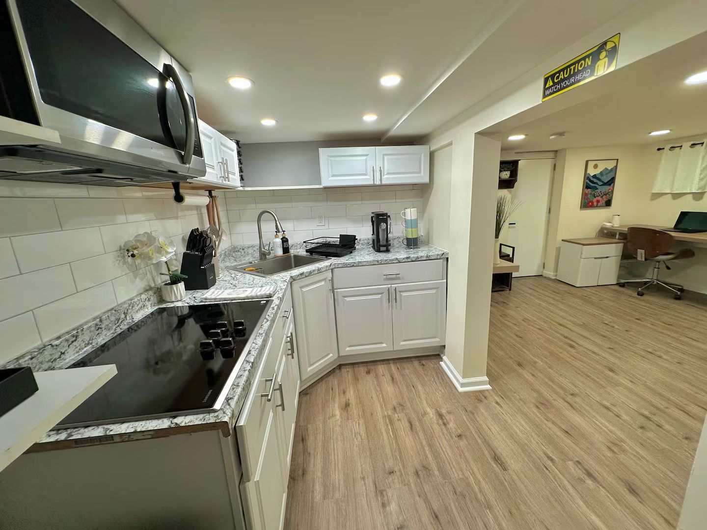 A modern kitchen with white cabinets, a black stove, and a microwave.