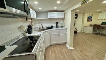 A modern kitchen with white cabinets, a black stove, and a microwave.