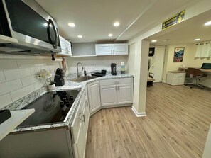 A modern kitchen with white cabinets, a black stove, and a microwave.
