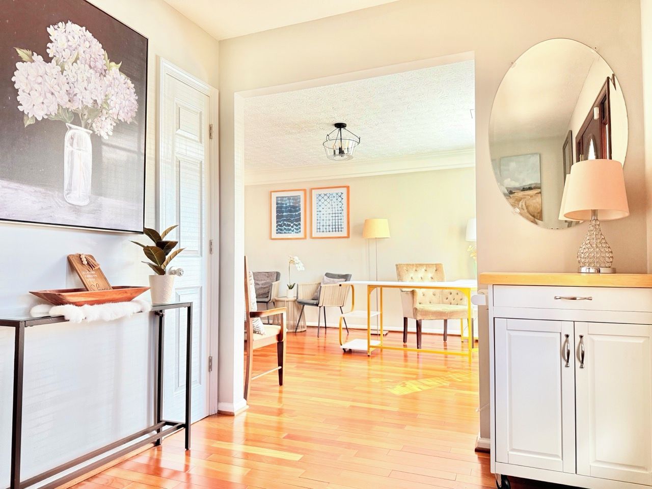A spacious living area with a wooden floor, a dining table, and a white cabinet.