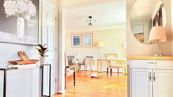 A spacious living area with a wooden floor, a dining table, and a white cabinet.