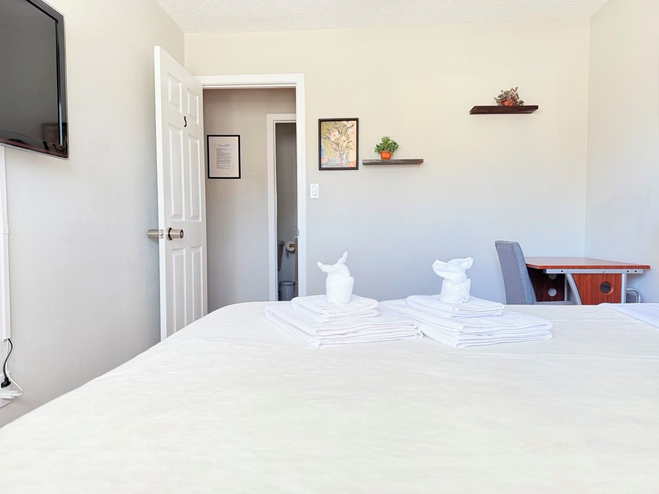 Una habitación de hotel con cama, escritorio, silla, televisión y puerta.
