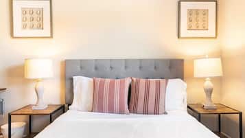 A hotel room with a large bed, two bedside tables with lamps, and framed artwork on the walls.