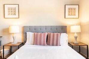 A hotel room with a large bed, two bedside tables with lamps, and framed artwork on the walls.