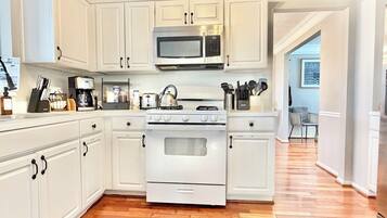 A kitchen with white cabinetry, a stainless steel microwave, a stove, and a toaster.