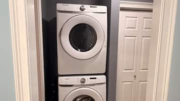 A laundry room with two stacked washing machines and a door in the background.