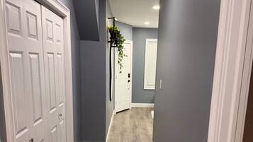 Un couloir avec un plancher en bois, des murs gris et des portes blanches.