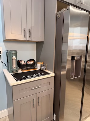 A kitchen with a stainless steel refrigerator, a coffee machine, and a sign that reads 'Coffee Bar'.