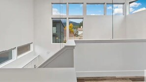 Un intérieur moderne avec un escalier menant à un balcon doté de grandes fenêtres.