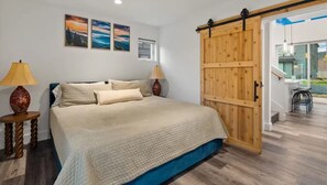A bedroom with a bed, two bedside lamps, a wooden door, and a view of the outside. - Entire Home in Whitefish, Montana (Whitefish)