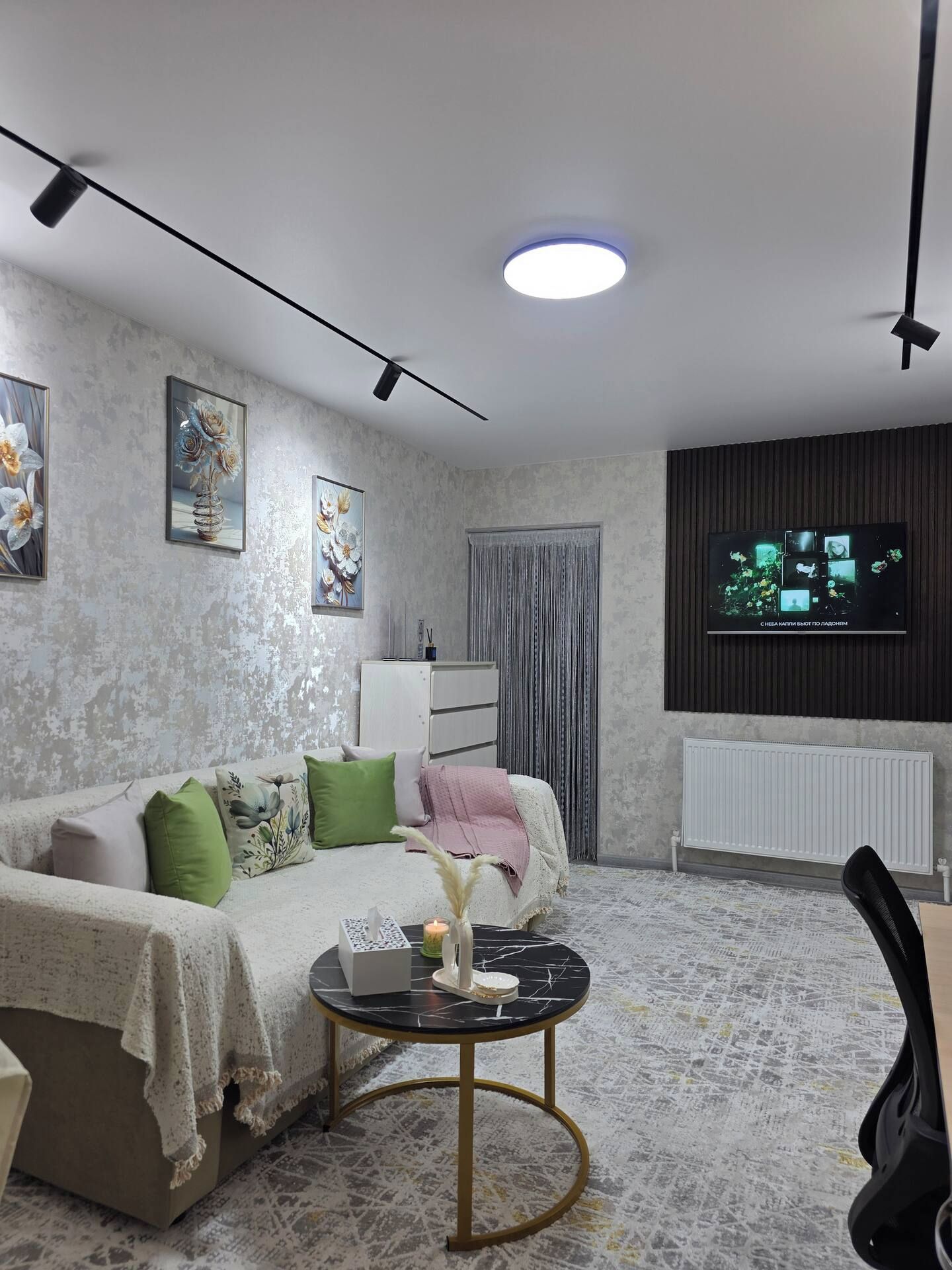 Un salon moderne avec un canapé, une table basse et un téléviseur fixé au mur.
