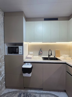 A compact kitchen with a microwave, sink, and cabinets.