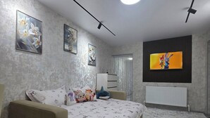 Een slaapkamer met een bed, een dressoir, een radiator en een televisie aan de muur.