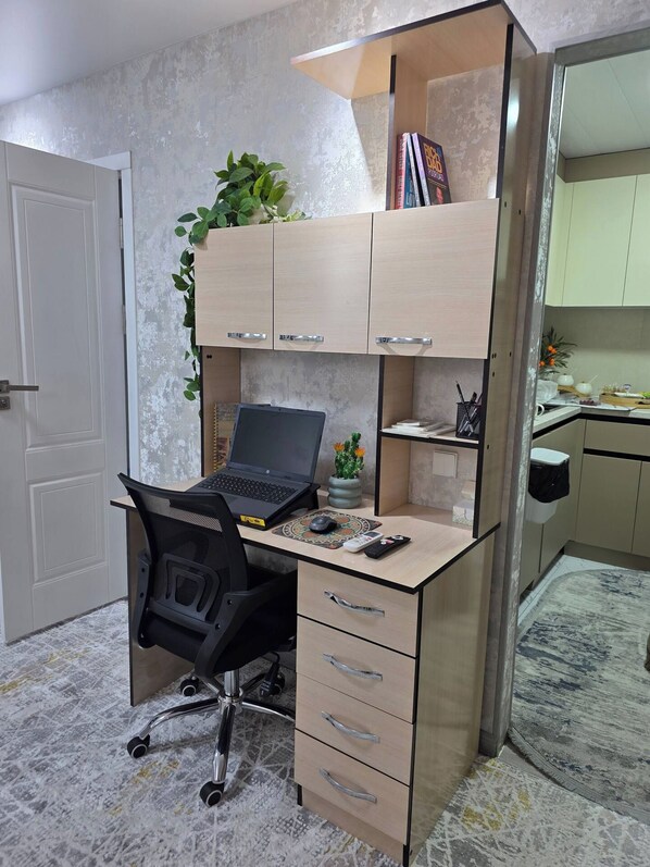 Un espacio de oficina funcional con escritorio, silla, computadora portátil y armarios de almacenamiento.