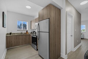 Eine moderne Küche mit Einbaukühlschrank, Holzschränken, einem Fenster und Blick auf die Stadt.
