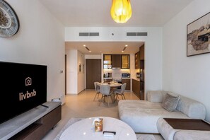 Ein modernes Wohnzimmer mit Flachbildfernseher, einer Couch, einem Couchtisch und einem Essbereich mit Stühlen.