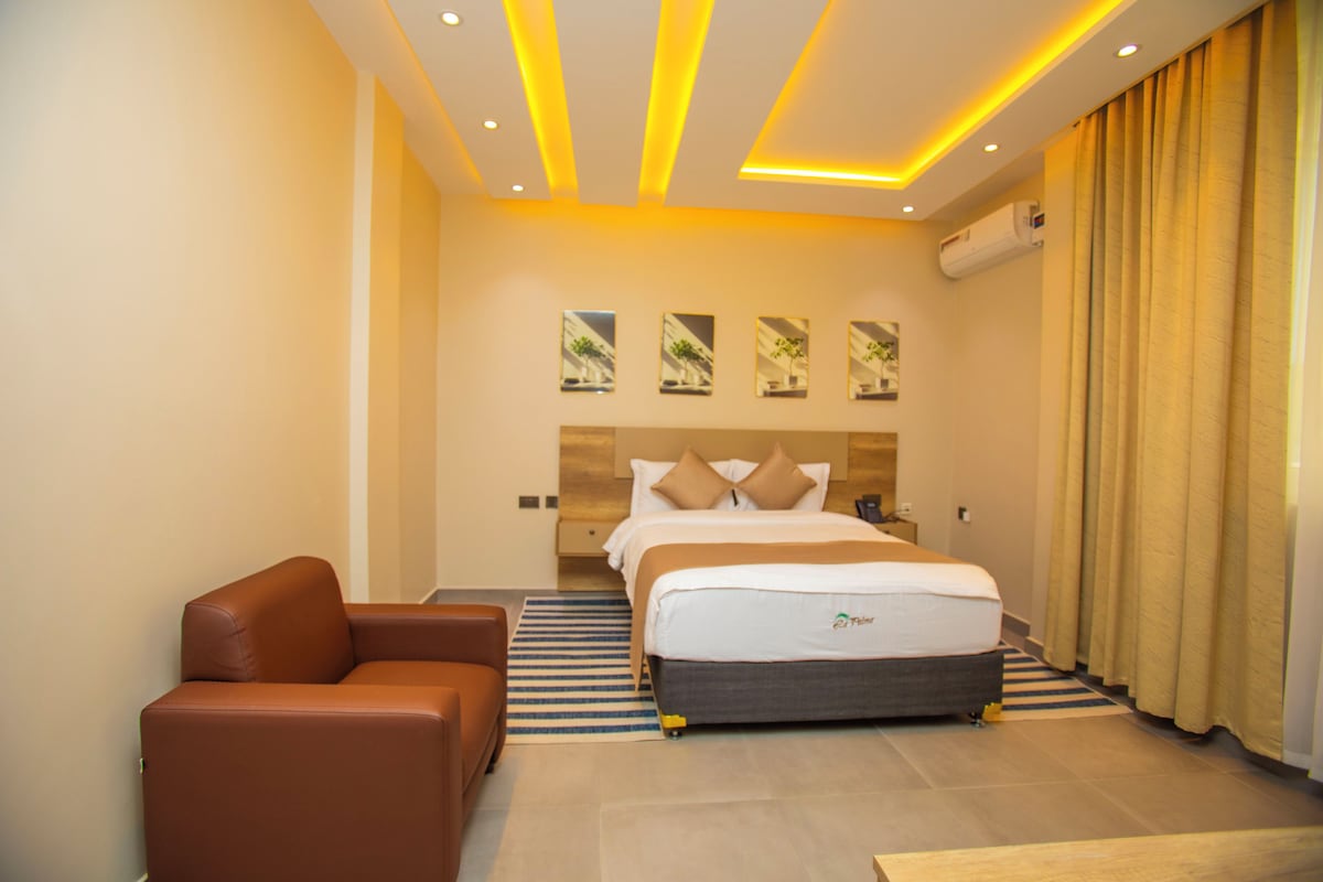 Una habitación de hotel con cama, sofá y aire acondicionado de pared.