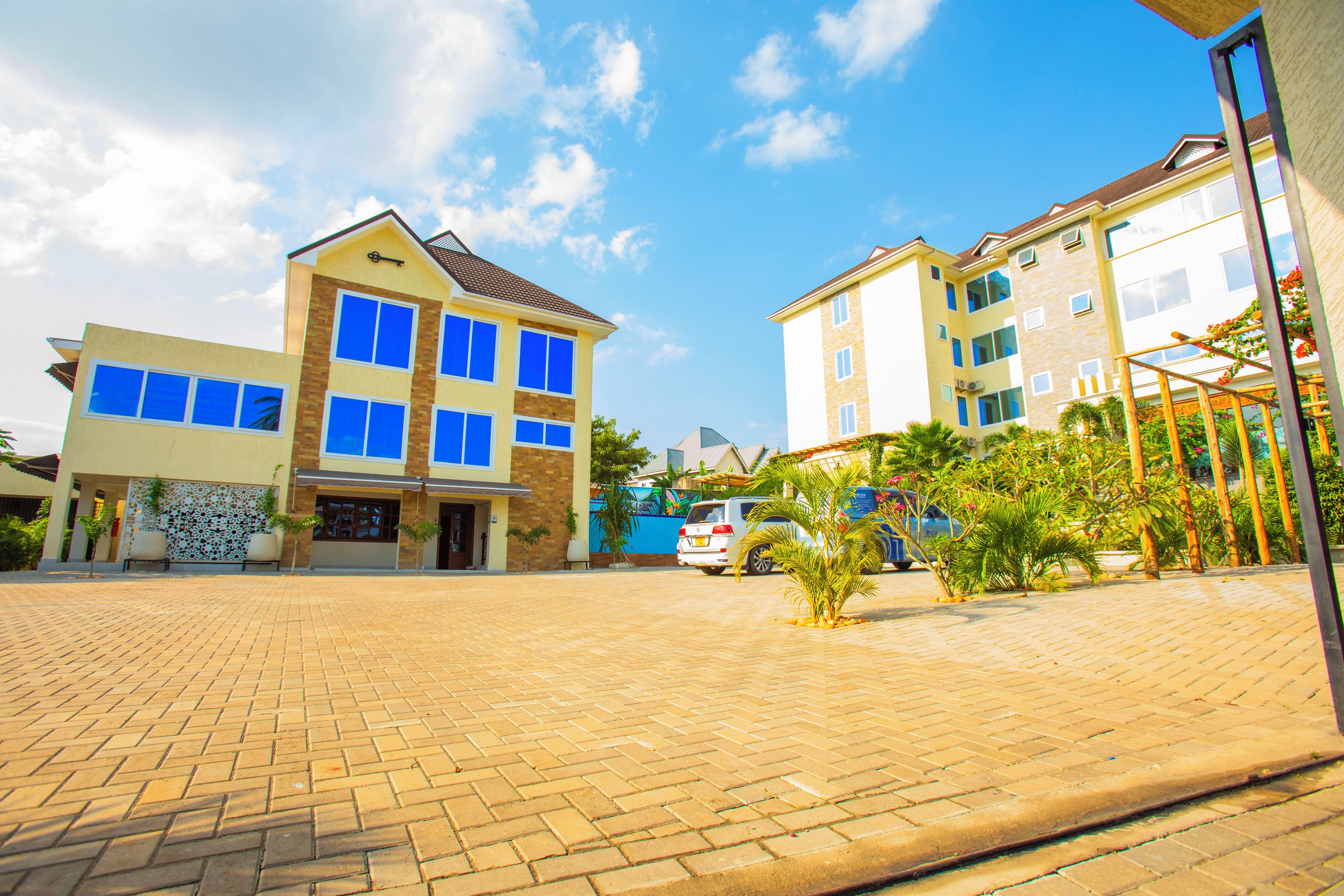 A multi-story building with a paved courtyard, large windows, and a clear sky.