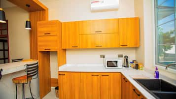 Een moderne keuken met houten kastjes, een wit aanrecht, een magnetron, een spoelbak en een raam met uitzicht op de omgeving.