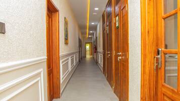 A long, narrow hallway with wooden doors on both sides, leading to a bright room at the end.