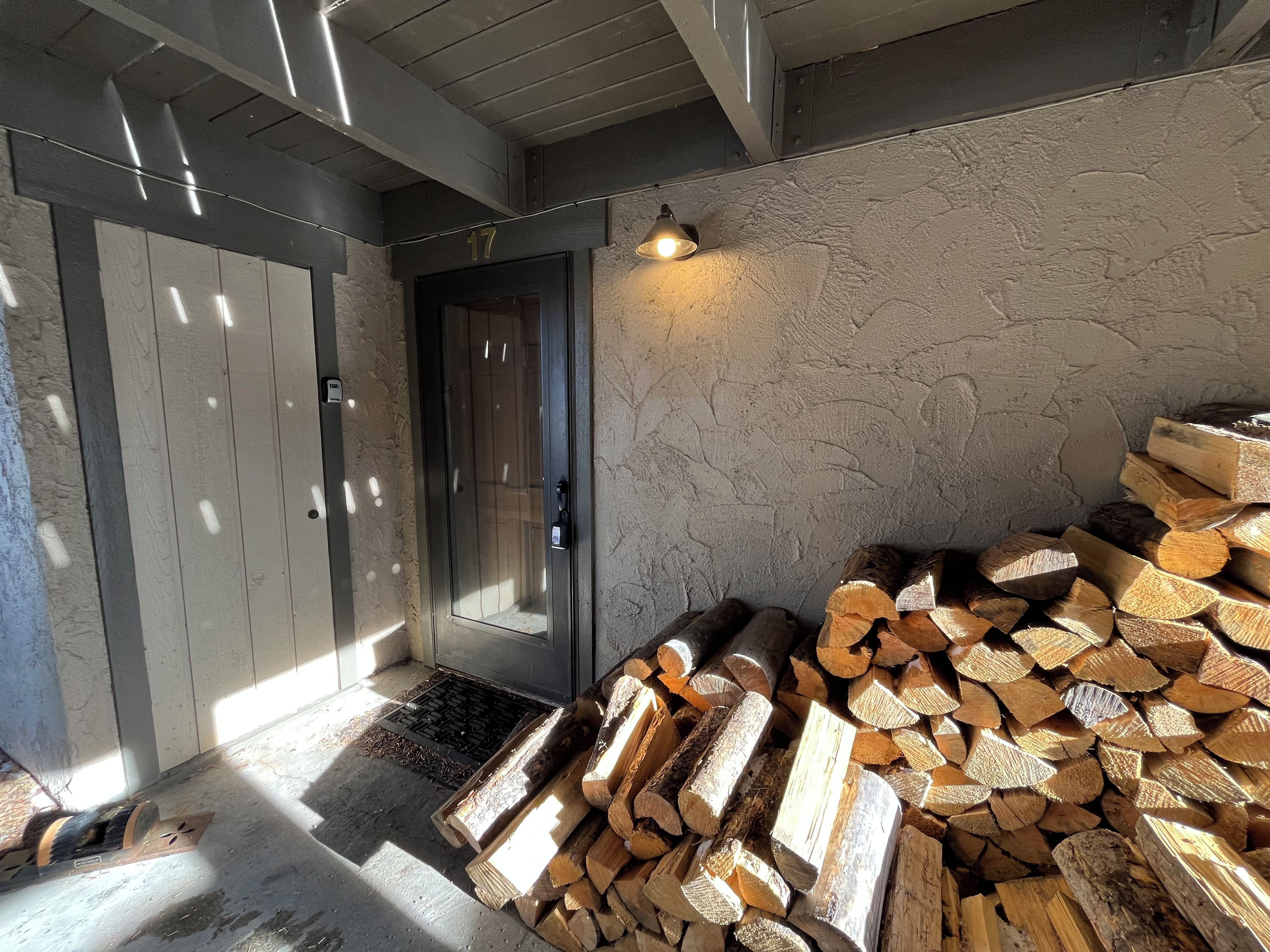 Una habitación con una puerta, una pila de leña y un muro con textura.