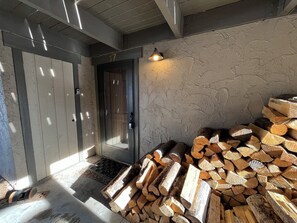 A room with a door, a stack of firewood, and a textured wall. - Big Sky Adventurer's Retreat on Big Sky Golf Course (Big Sky)