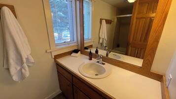 Une salle de bain avec un lavabo blanc, un meuble-lavabo en bois et un grand miroir.
