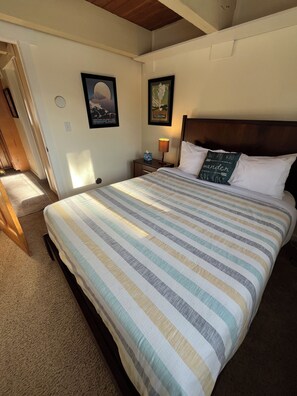 A neatly made bed with a striped bedspread, a wooden headboard, and two framed pictures on the wall. - Big Sky Adventurer's Retreat on Big Sky Golf Course (Big Sky)