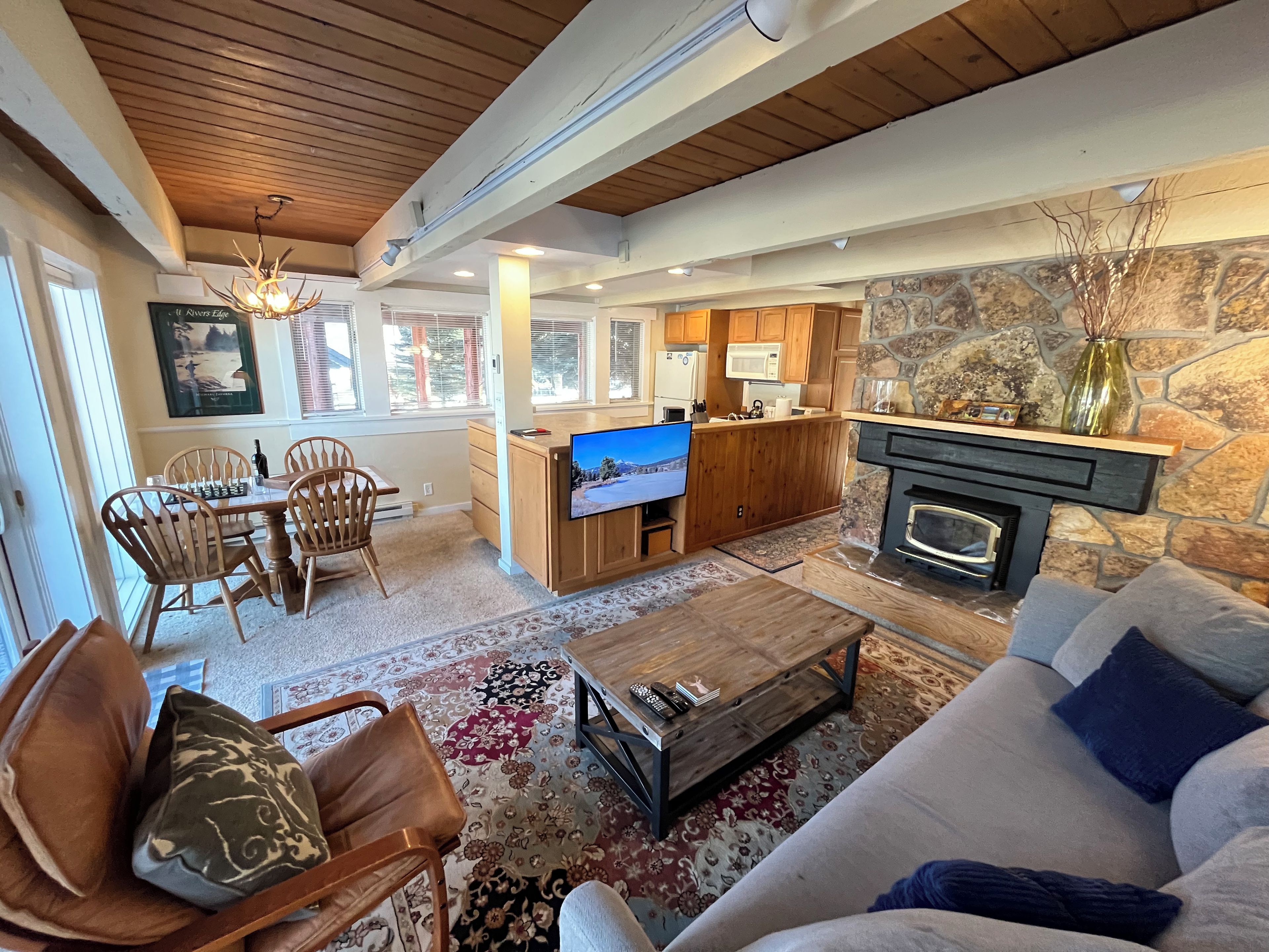 Amplia sala de estar con chimenea, televisor y comedor con sillas y una mesa.