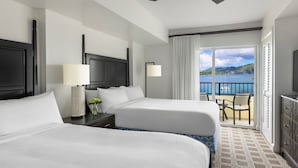 Habitación de hotel con dos camas, un balcón y vistas al mar, además de una televisión.
