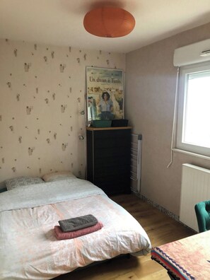 A bedroom with a bed, a poster on the wall, a radiator, and a window. - Gatsby Apartment (Évian-les-Bains)