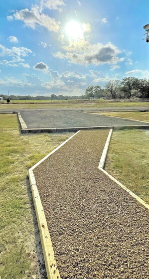 A gravel area with a wooden border, surrounded by grass and a clear sky. - Sunrise Yellow Cabin #5 Quitman, Tx (Quitman)