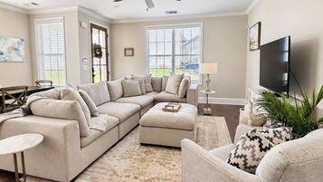 A living room with a sectional sofa, a round coffee table, a side chair, a television, and a ceiling fan.