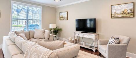 A living room with a sofa, armchair, TV, and a ceiling fan.