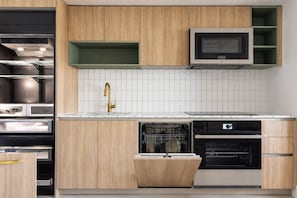 Una cocina moderna con armarios de madera, campana extractora de acero inoxidable, lavavajillas integrado y microondas.