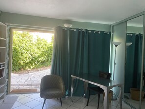 Ein Zimmer mit Esstisch, Stuhl, Lampe und Blick auf Grünflächen.