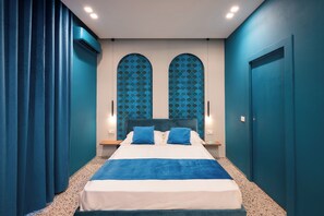 A bedroom with a bed, two nightstands, a window with a blue pattern, and a door. - Alma Napoli al Centro Storico (Naples)