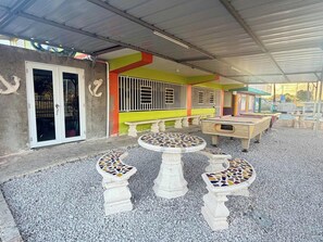 An outdoor patio area with a covered seating area, a pool, and a door leading to an interior space. - Spacious & Colorful Haven with Pool Tables & Pool (Cabo Rojo)