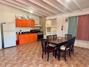 A kitchen with a dining table, chairs, and a refrigerator. - Spacious & Colorful Haven with Pool Tables & Pool (Cabo Rojo)