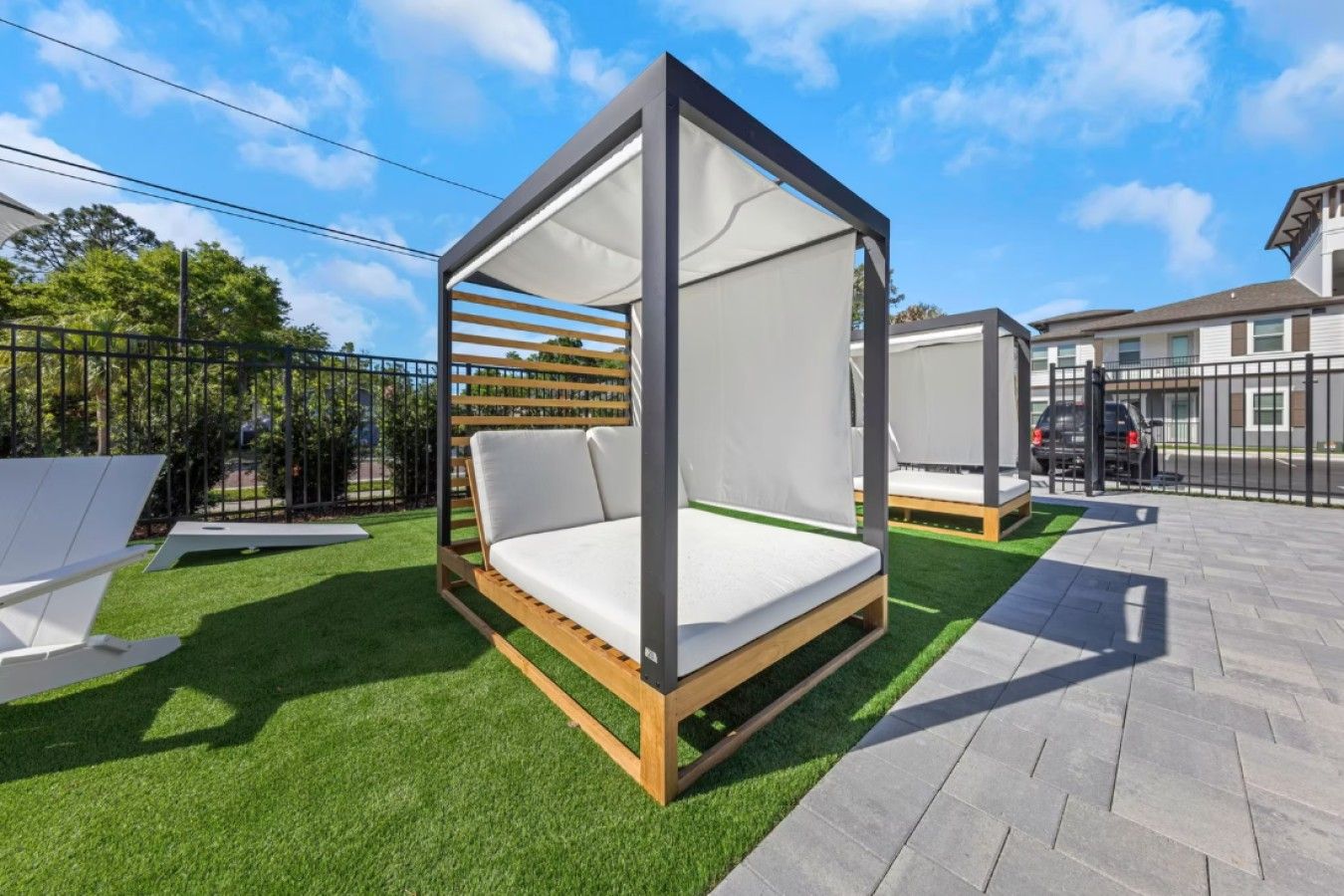 Un espace extérieur moderne aménagé avec un banc en bois et une structure en forme de tonnelle.
