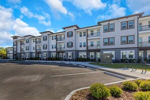 A multi-story residential building with a parking lot in front. - Relaxing 2BR Stay | Pool, Gym & Free Parking (Largo)